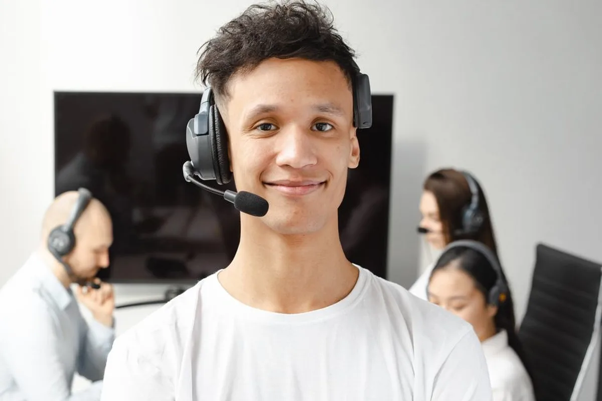 Un conseiller client souriant portant un casque téléphonique répond à une question.