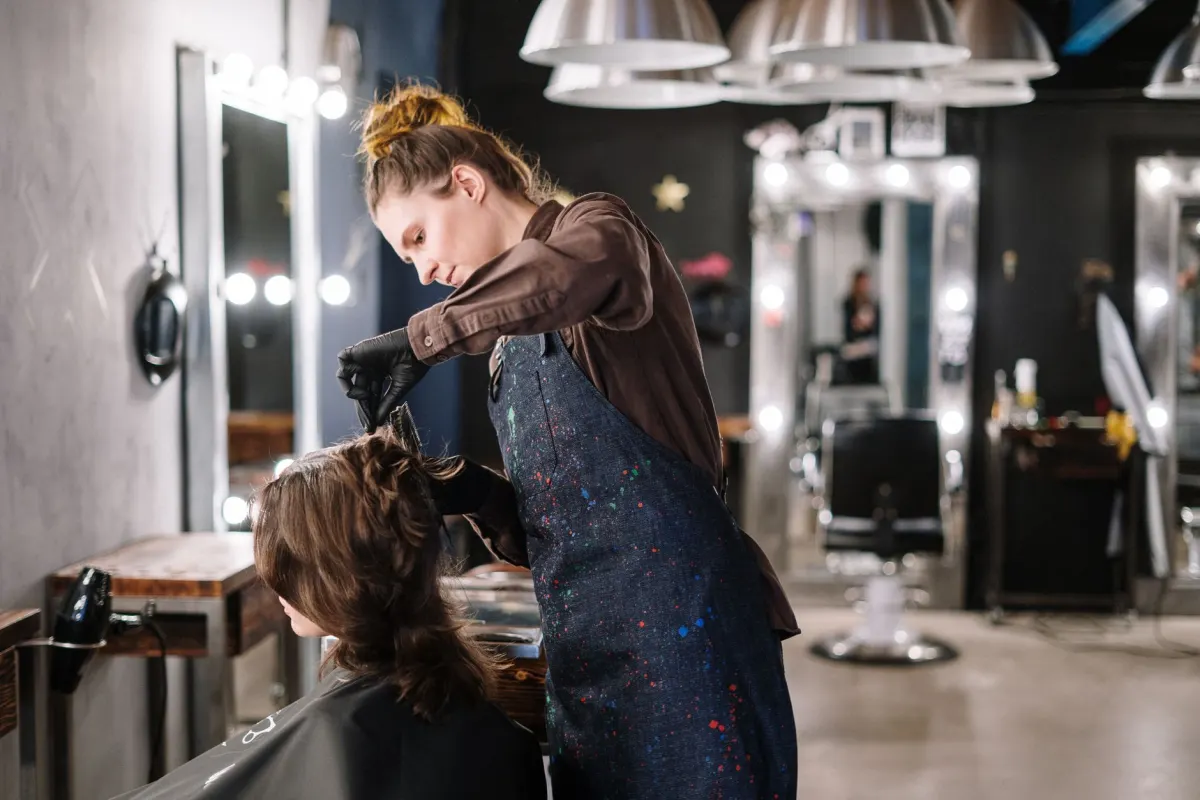 Coiffeuse réalisant une coupe de cheveux dans un salon de coiffure
