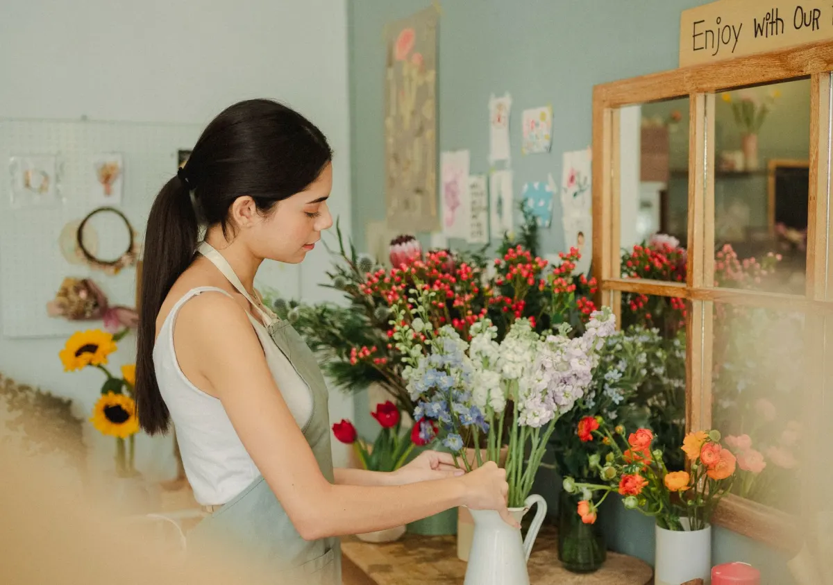 Fleuriste composant un bouquet dans sa boutique de commerce de proximité