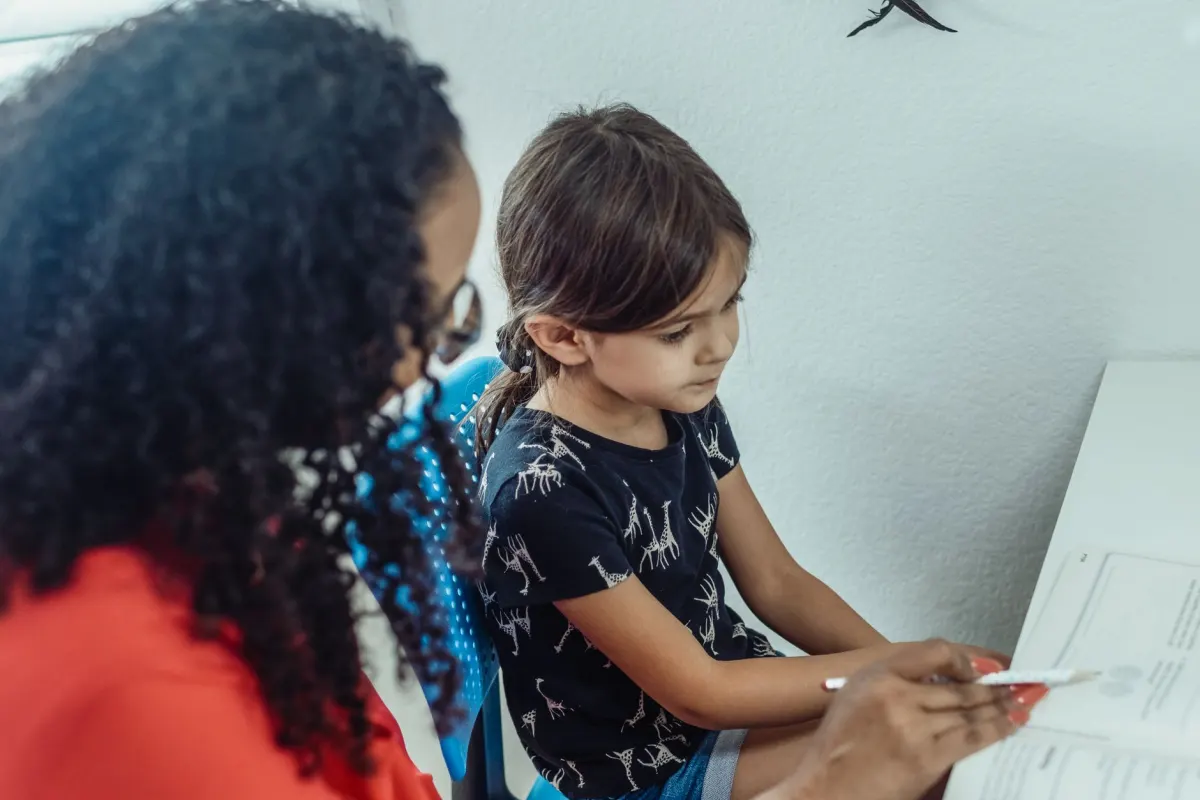 Professeure de soutien scolaire aidant une jeune élève à faire ses devoirs