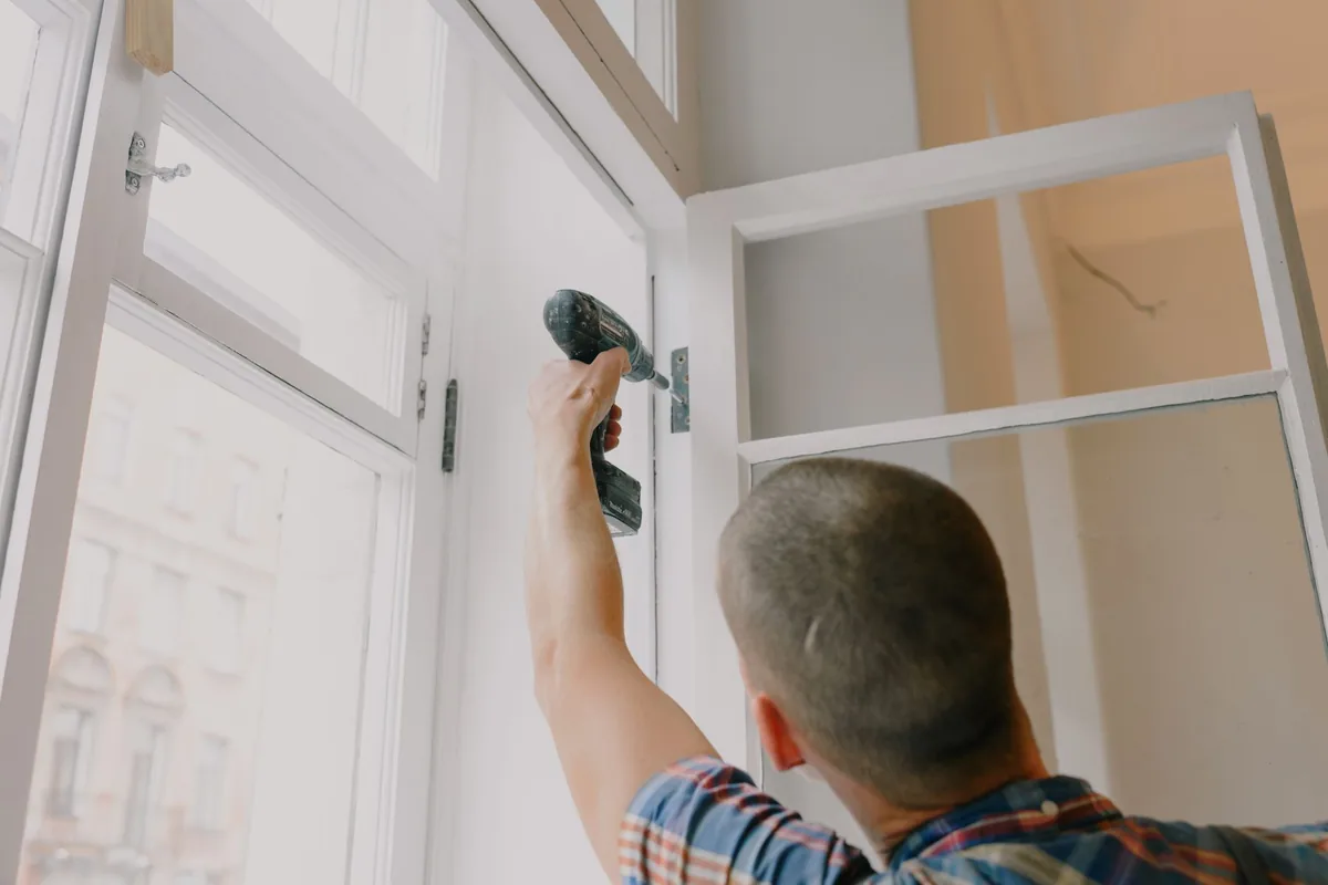 Menuisier posant une fenêtre en bois sur un chantier