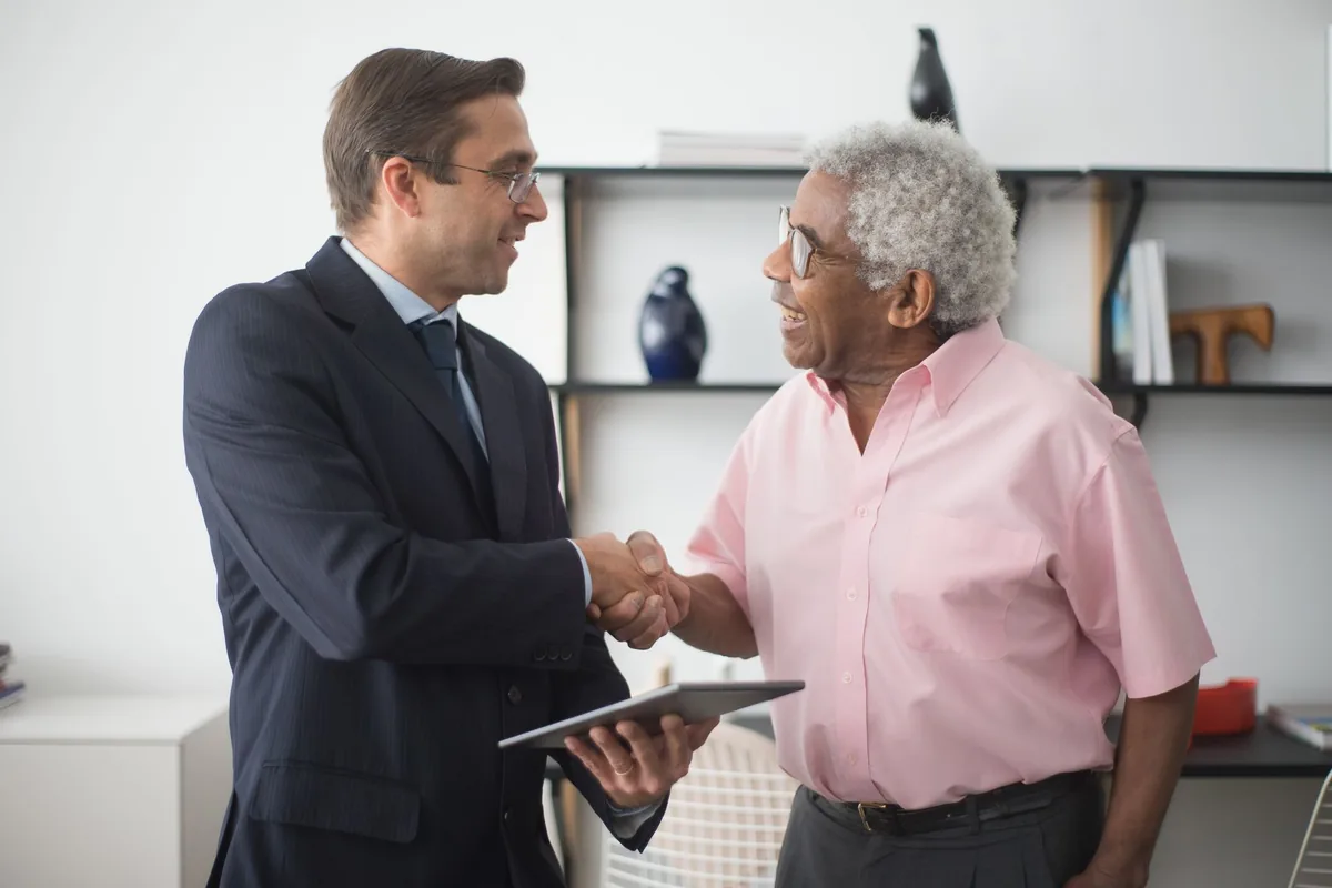 Agent d'assurance serrant la main d'un client satisfait dans son bureau