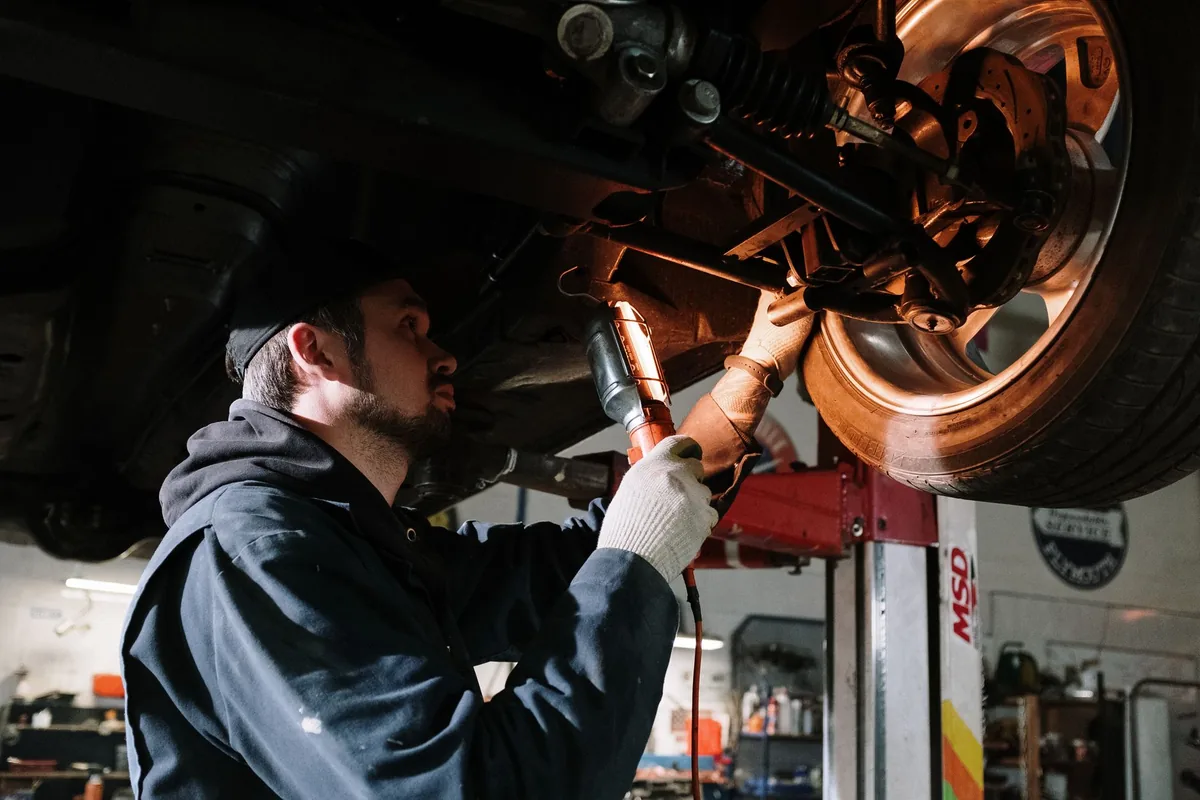 Technicien d'un centre auto effectuant l'entretien d'un véhicule en atelier