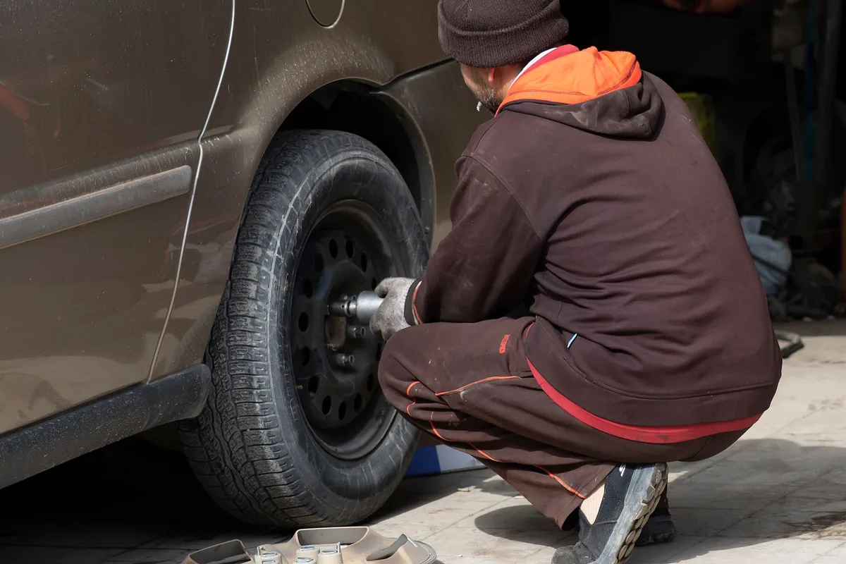 Technicien pneumaticien montant un pneu sur une roue dans un atelier spécialisé