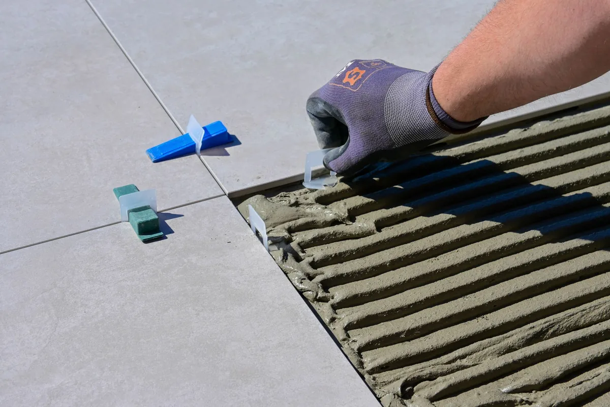 Carreleur posant du carrelage au sol dans une pièce en rénovation