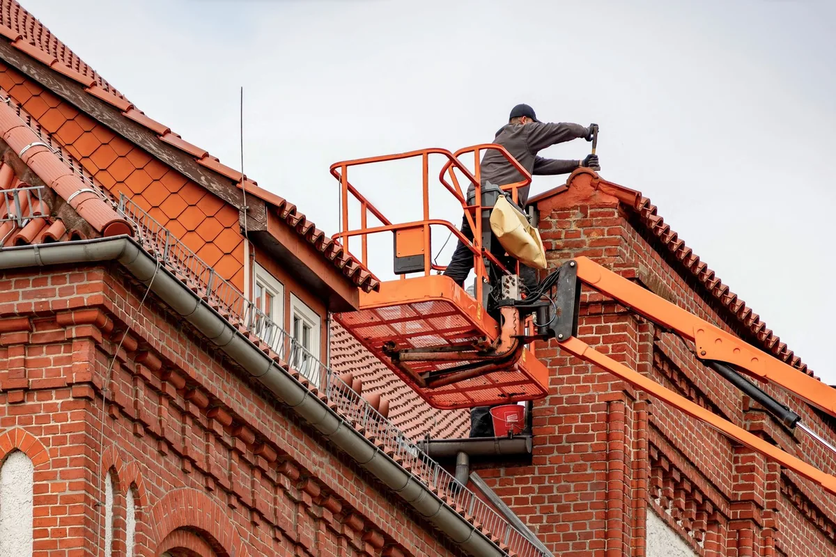 Couvreur réparant des tuiles sur le toit d'une maison