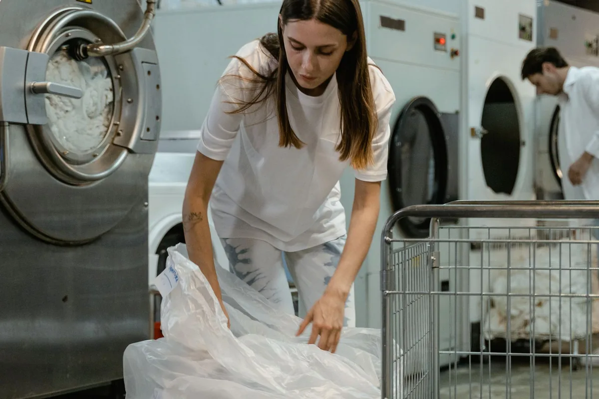 Employée de pressing triant du linge propre parmi les machines à laver industrielles