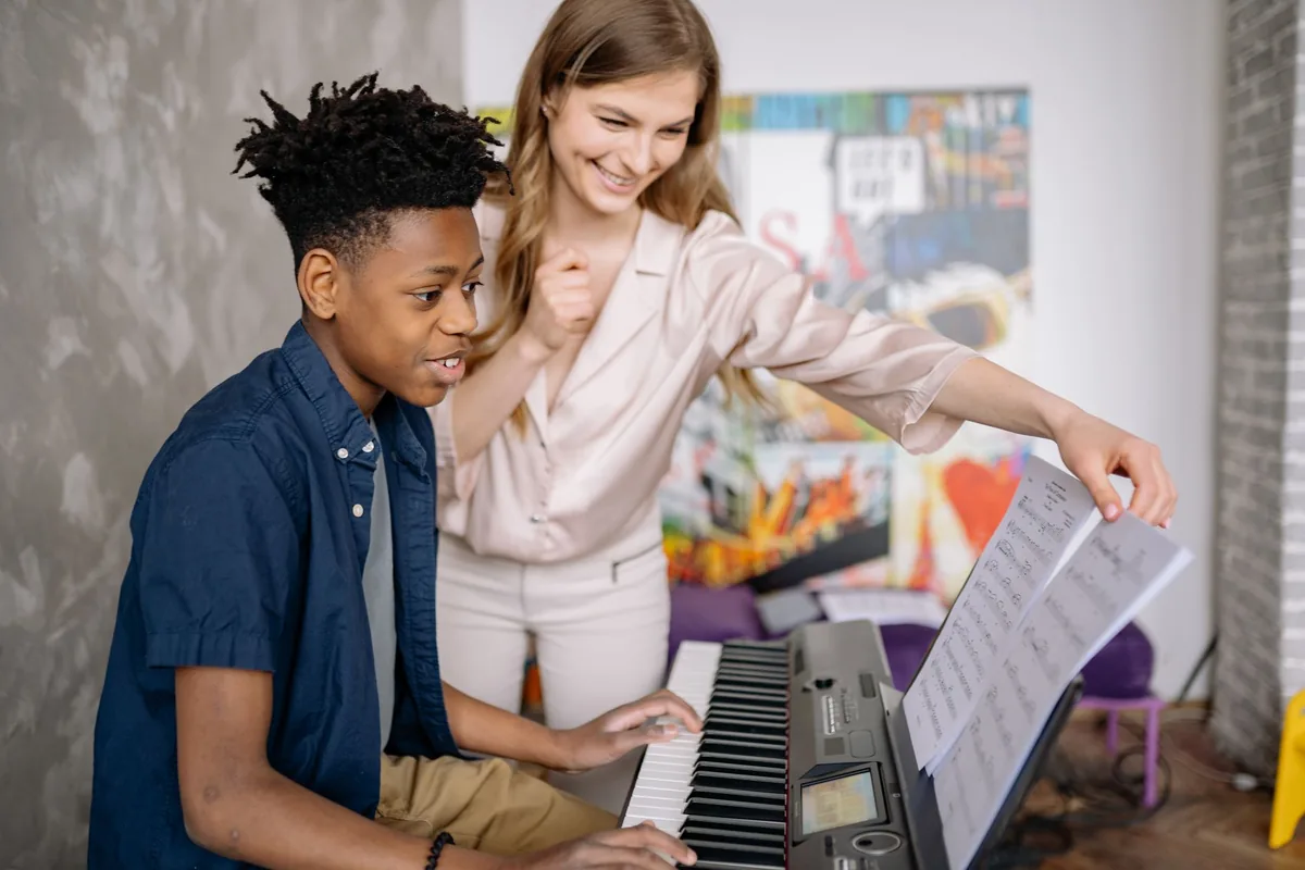 Professeure de musique donnant un cours de piano à une jeune élève dans son école