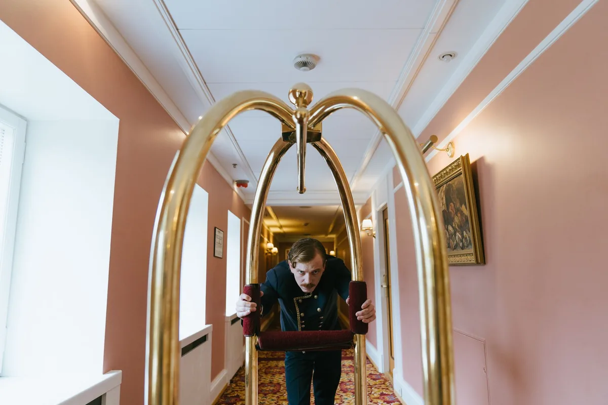 Bagagiste poussant un chariot à bagages dans le couloir d'un hôtel
