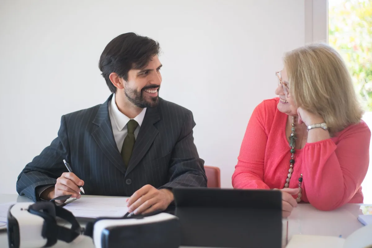 Notaire souriant faisant signer un document à sa cliente dans son bureau
