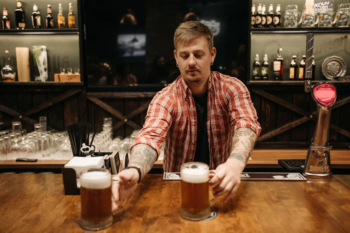 Barman servant deux pintes de bière au comptoir d'un bar convivial