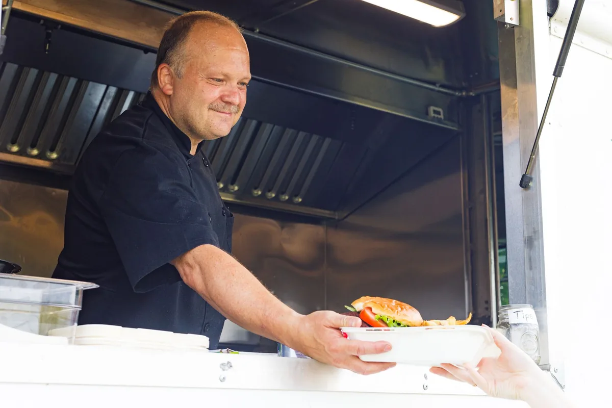 Cuisinier servant un client au comptoir d'un food truck