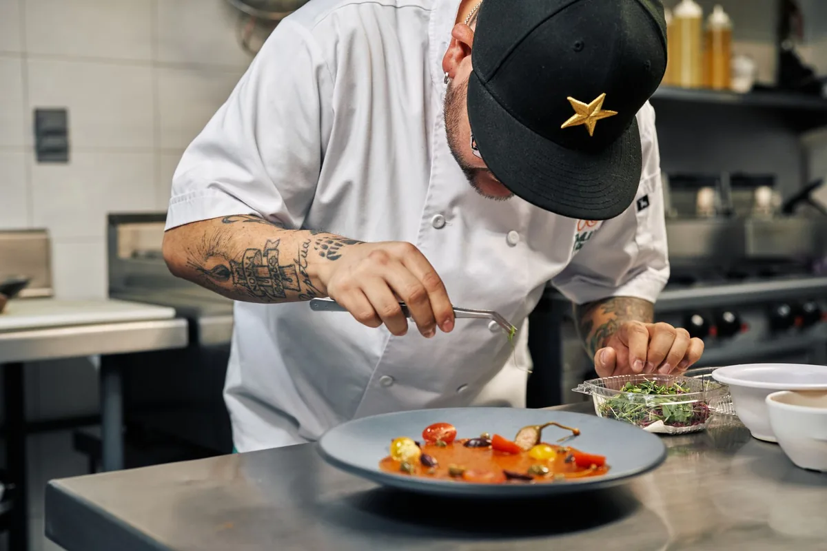Chef cuisinier dressant un plat gastronomique avec précision en cuisine professionnelle