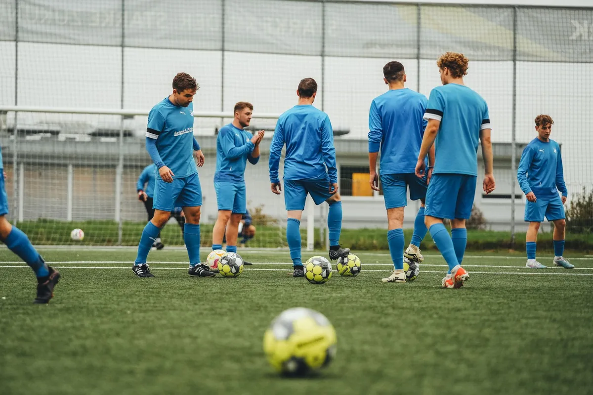 Entraîneur bénévole encadrant une équipe de jeunes lors d'un entraînement de club sportif