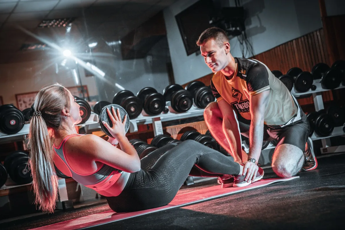Coach sportif accompagnant un client lors d'une séance de musculation personnalisée