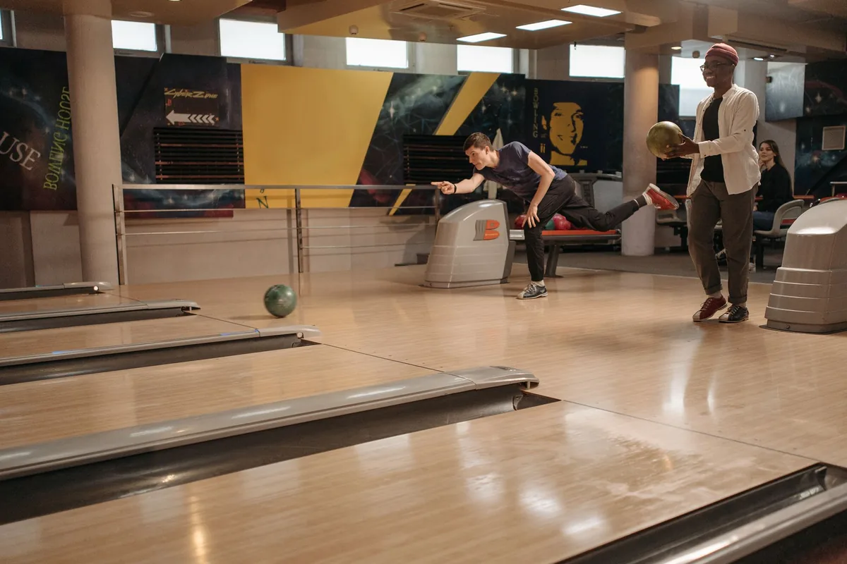 Groupe d'amis riant ensemble pendant une partie de bowling en centre de loisirs indoor
